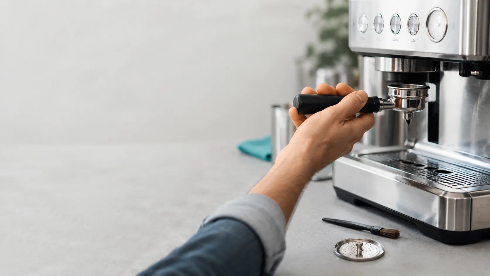 Hands removing the portafilter from a home espresso machine to diagnose a weak shot